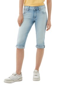Capris de denim azul claro con puños enrollados, cinco bolsillos y un ajuste slim. Se llevan con zapatillas blancas para un look casual.