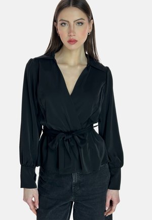 Blouse noire en tissu lisse, dotée de manches longues, d'un col en V et d'une ceinture à nouer à la taille pour un look ajusté.
