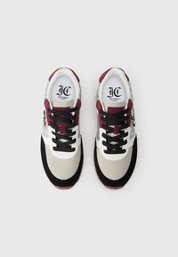 Par de zapatillas multicolores con cordones negros, acentos en gris, blanco, burdeos y purpurina plateada, vistas desde arriba sobre un fondo blanco.
