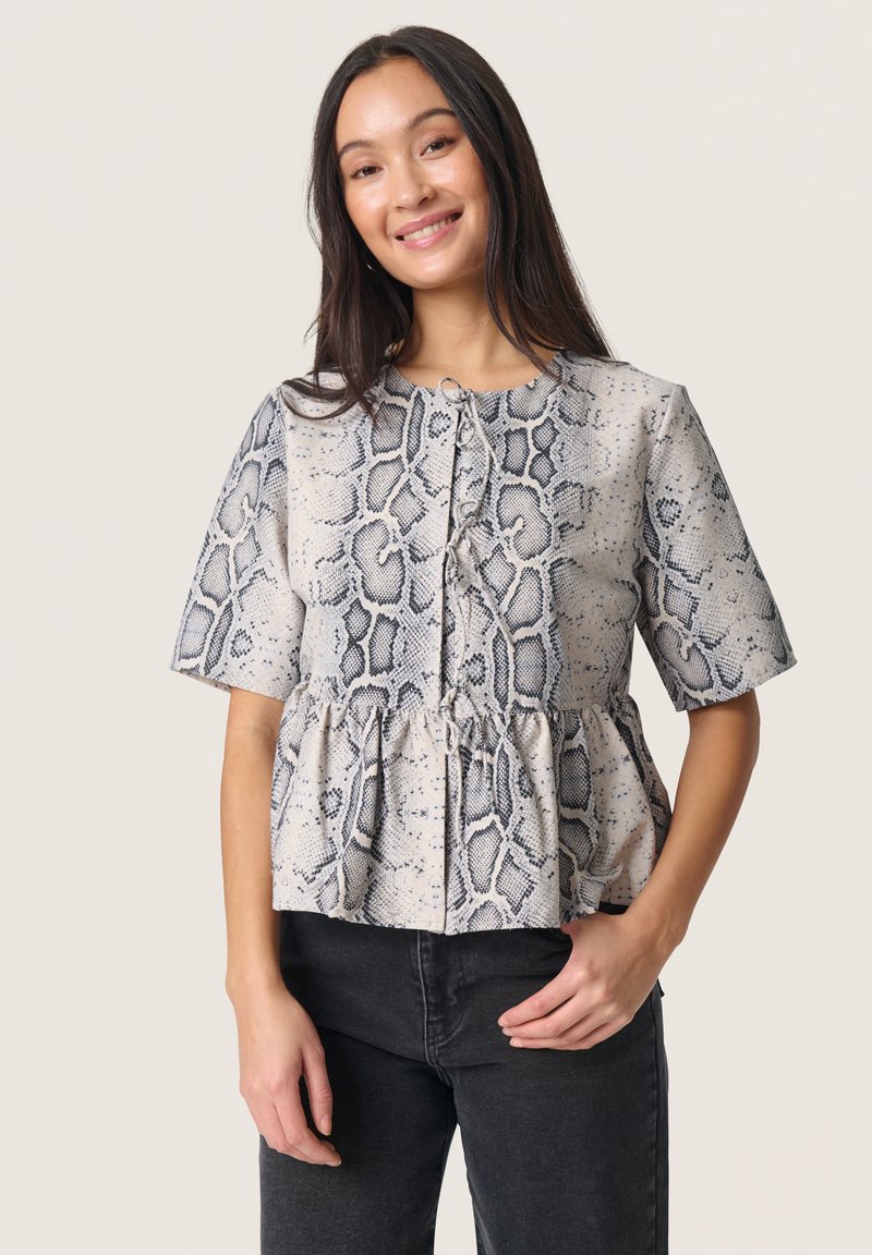 Haut peplum à manches courtes en imprimé serpent, présentant un schéma de couleurs gris clair et noir, un tissu texturé et une fermeture à boutons sur le devant.