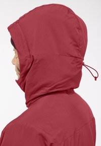 Veste à capuche rouge à la texture lisse, dotée d'un cordon de serrage. Le design met en avant une silhouette épurée sans motifs visibles.