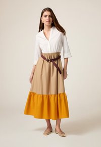 Knielanges Kleid mit drei Viertel Ärmeln, einem weißen Oberteil, beigem Taillenteil und einem hellgelben, rüschierten Saum, ausgestattet mit einem geflochtenen kastanienbraunen Gürtel.