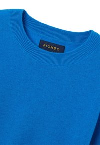 Felblau gebreid sweater met een ronde hals en geribbelde randen. Heeft een label met de tekst "PIOMBO" in het geel op een donkere achtergrond.