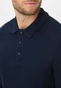 Polo shirt blu navy realizzato in tessuto a maglia testurizzata, dotato di colletto, patta con tre bottoni e maniche corte.
