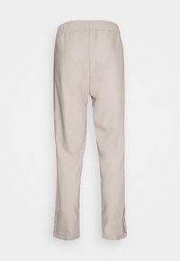 Beige, lehké kalhoty s elastickým pasem, vybavené bočními knoflíky na manžetách pro nastavitelné přizpůsobení a hladkou, matnou texturou.