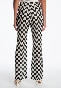 Zwart-wit gestreepte broek met een golvend ontwerp, voorzien van een hoge taille en uitlopende pijpen, gemaakt van een textuurstof.