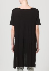 Černá tuniková blůza s krátkým rukávem a volným střihem, s kulatým výstřihem a delším zadním dílem, vyrobená z měkké a lehké látky.
