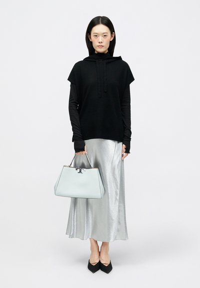 Sort hættebluse, lange ærmer, sølvfarvet satin-nederdel, sorte spidse sko, lyseblå håndtaske med sølv hardware og en struktureret form.