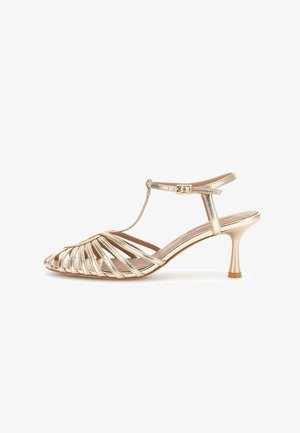 Sandalo con tacco kitten aperto con cinturino dorato, fibbia alla caviglia e cinturino a T, caratterizzato da un tacco sottile curvo e un design in pelle intrecciata.