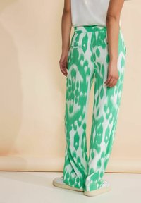 Gröna och vita mönstrade vida byxor med elastisk midja, som har två bakfickor och ett smidigt, lätt tyg.