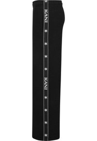 Črne trenirke z ravnim krojem, ki imajo beli logotip in vzorec z zvezdami ob strani, narejene iz mehkega materiala.