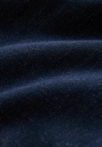 Jūrinei mėlyna medžiaga su švelniu, smulkiu tekstūru ir subtiliu blizgesiu. Pasižymi nežymiu tamprumu ir lygiu paviršiumi su audimo detalėmis.