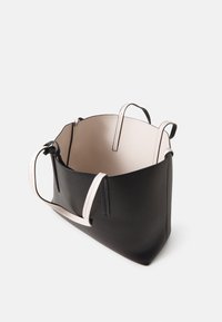 Czarna skórzana torba tote o gładkiej fakturze, beżowe wnętrze i podwójne uchwyty na górze. Posiada przestronny otwarty design bez zapięcia.