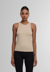Beige ärmelloses Tanktop mit rundem Ausschnitt, aus glattem Stoff gefertigt. Verfügt über ein kleines Logo auf der Vorderseite und ein figurbetontes Design.