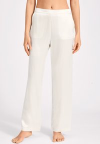 Pantalons larges couleur beige clair en tissu lisse et brillant. Dotés d'une taille élastique et de poches latérales. Design longueur sol.