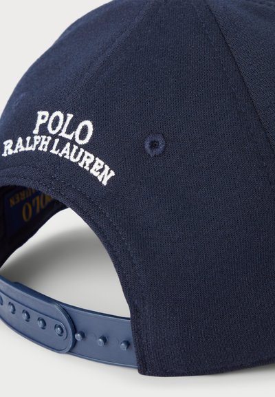 Marineblå keps med broderad "Polo Ralph Lauren"-logotyp, texturerad tyg, justerbar snapback-stängning och ventilationshål.