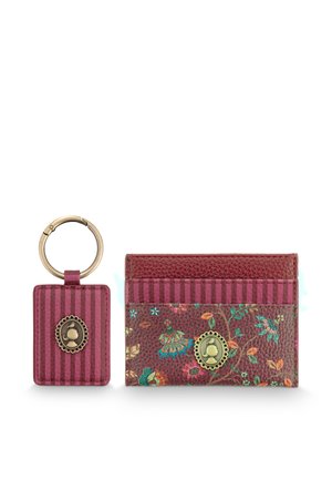 Keyring and cardholder set in dark red leather with striped and floral patterns, each featuring a small round brass emblem with a character silhouette.