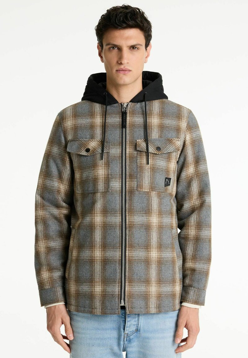 Karierte Flanelljacke in Grau-, Braun- und Cremetönen, ausgestattet mit einer schwarzen Kapuze, zwei Brusttaschen und einem Reißverschluss vorne.