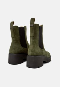 Stivaletti alla caviglia in suede verde con pannelli laterali in elastico nero, suola in gomma nera chunky e linguetta sul tallone.