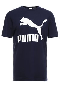 Camiseta de algodón azul marino con un gran logo blanco de "PUMA" y la silueta de un puma saltando sobre el texto. Mangas cortas, cuello redondo.