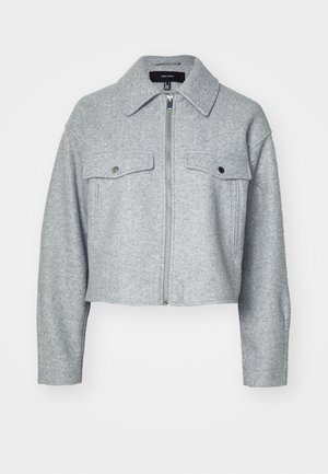 Saplēsts pelēks žakets, izgatavots no mīkstas auduma, ar priekšējo rāvējslēdzēju, divām krūšu kabatām ar sprādžu aizdari un uzgaļveida apkakli.