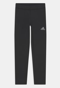 Leggings noirs en tissu extensible, dotés d'une taille haute et d'un petit logo Adidas argenté sur la jambe gauche. Texture lisse, sans motifs.