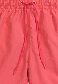 Korálowe szorty kąpielowe wykonane z lekkiego materiału. Posiadają elastyczny pas, podwójne sznurki do regulacji i gładką, lekko błyszczącą teksturę.