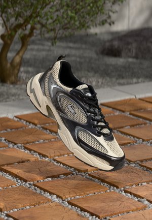 Beige és fekete sneaker, hálós felsőrésszel, texturált dizájnnal, fűzős záródással és logóval, mintás kőfelületen elhelyezve.