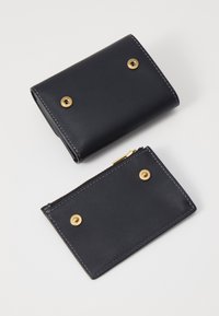 Navy leather wallet with gold-tone hardware, featuring a fold-over design and a small zippered pouch with similar button accents.