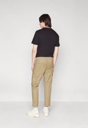 Black short-sleeve t-shirt paired with khaki cargo pants featuring side pockets, slim fit, and white sneakers with green accents.