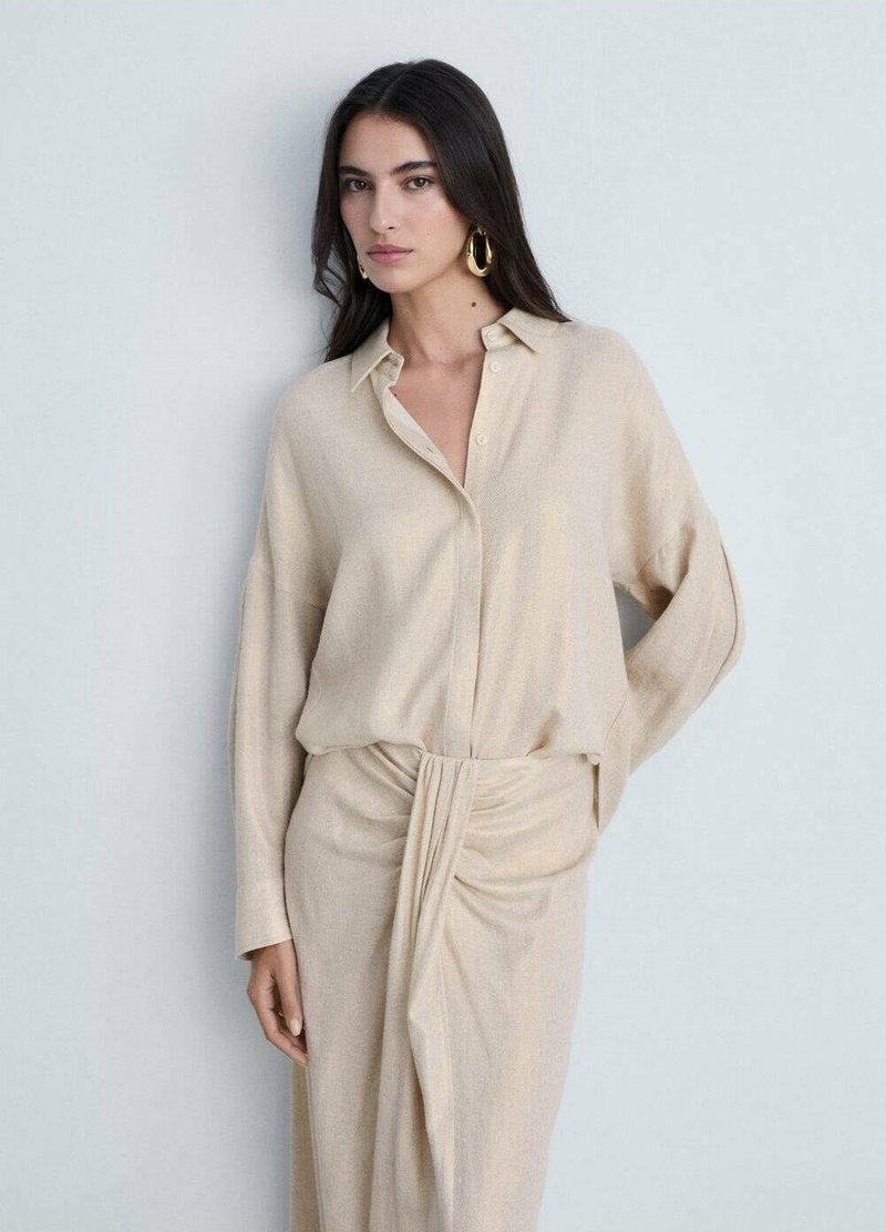 Beige long-sleeve shirt with a button-down collar, paired with a matching midi skirt featuring a twisted knot detail in the front.