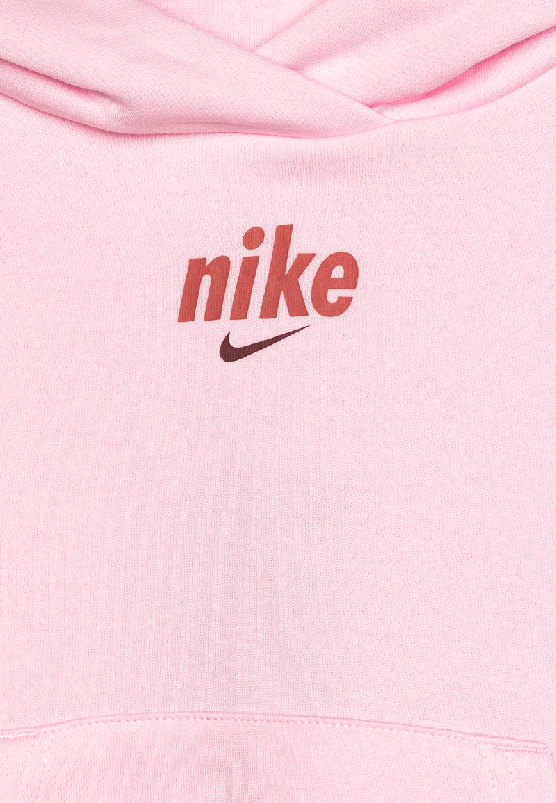 Tessuto rosa con il testo "nike" rosso e un logo swoosh Nike marrone stampato sopra una cucitura curva.