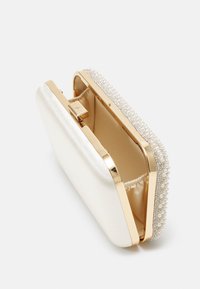 Kovový zlatý klipsový uzávěr, sametový perleťový povrch, ozdobený řadou malých perel a krystalů podél horního okraje.