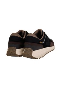 Schwarze und braune Turnschuhe mit einer strukturierten Oberseite, gepolstertem Schaft und einer dicken, beigefarbenen Gummisohle. Mit einem "FAGUO"-Logo an der Ferse.