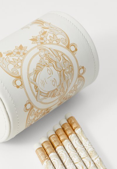 White cylindrical pencil case with gold ornate design featuring a face. Accompanied by gold-accented patterned pencils with erasers.