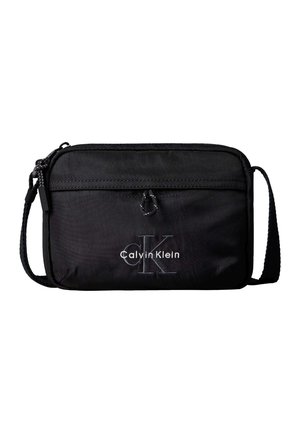 Czarna torba na ramię Calvin Klein z przednią kieszenią na suwak i regulowanym paskiem, z wyhaftowanym logo i małą tkaną pętelką nad kieszenią.