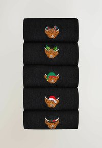 Sosete negre stivuite vertical, cu ilustrații cusute ale vacilor din Highlands purtând pălării festive și decorațiuni din fir colorat.