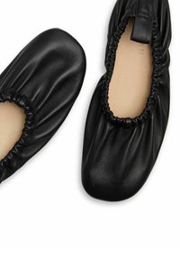 Bailarinas de cuero negro con una abertura elástica suave y fruncida, y un diseño de punta redondeada. Textura suave y apariencia minimalista.