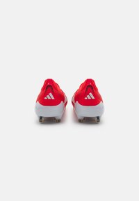 Red athletic shoes with a textured mesh upper, white accents, and a molded heel. Features three diagonal stripes on each side.