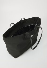 Black nylon tote bag with two long handles, a zip closure, and an interior compartment. Features silver logo detailing on the front.