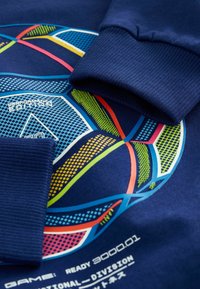 Marineblaue Sweatshirt mit gerippten Bündchen; zeigt farbenfrohe geometrische Muster und weißen, blauen und grünen Text auf der Vorderseite.