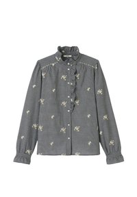 Chemise à manches longues à carreaux noir et blanc avec col à volants, broderie florale et boutonnière. Présente des poignets froncés et des coutures décoratives.