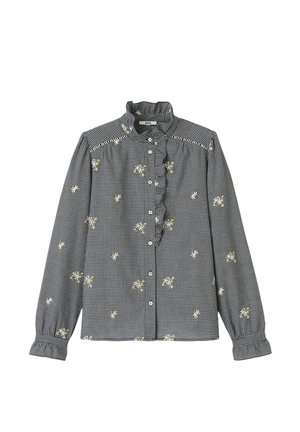 Chemise à manches longues à carreaux noir et blanc avec col à volants, broderie florale et boutonnière. Présente des poignets froncés et des coutures décoratives.