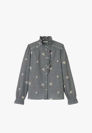 Chemise à manches longues à carreaux noir et blanc avec col à volants, broderie florale et boutonnière. Présente des poignets froncés et des coutures décoratives.