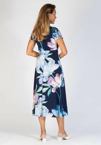 Mekko, jossa on kukkakuosi, lyhyet hihat, istuva yläosa ja valuva hame tummansinisessä värissä, koristeltuna vaaleansinisin ja vaaleanpunaisin kukin.