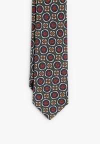 Corbata con patrón que presenta un fondo verde con diseños circulares en rojo, azul marino y blanco. Fabricada con una tela texturizada y con un extremo puntiagudo.
