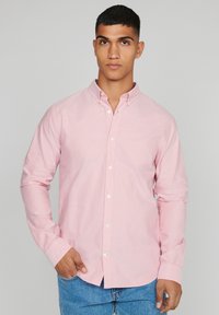 Lichtroze overhemdd blouse van een katoenmix, met een klassieke kraag, lange mouwen en witte knoopaccenten. Draag het met blauwe spijkerbroeken.