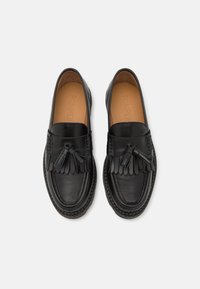 Mustad mustad nahast loafers, millel on kudumine tekstuur, esiküljel tutidetail ja sile sisemus, millel on silustatud brändinimi.