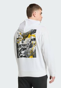 White hoodie with a graphic print on the back featuring black and yellow comic-style illustrations and lightning accents.