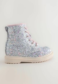 Botín plateado brillante con acentos rosas. Presenta cordones, un upper texturizado y una suela blanca gruesa con un dibujo en el relieve.